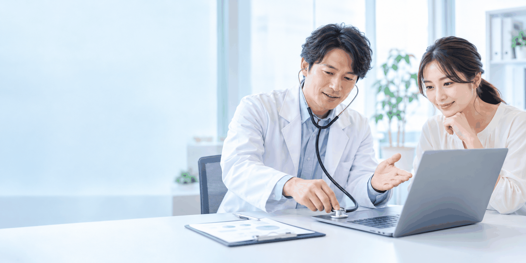 白衣の人物がノートPCに聴診器を当て、アプリの状態を確認している様子